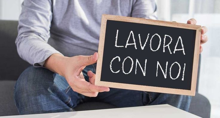 Una persona seduta tiene una lavagnetta con la scritta a gesso: Lavora con noi